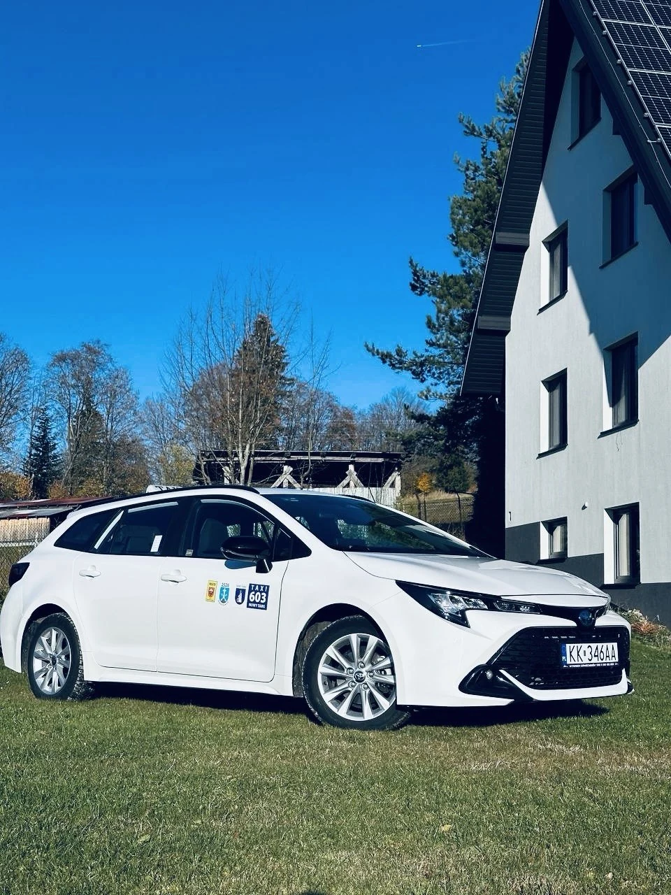 Белая Toyota Corolla с табличкой TAXI, вид спереди и сбоку